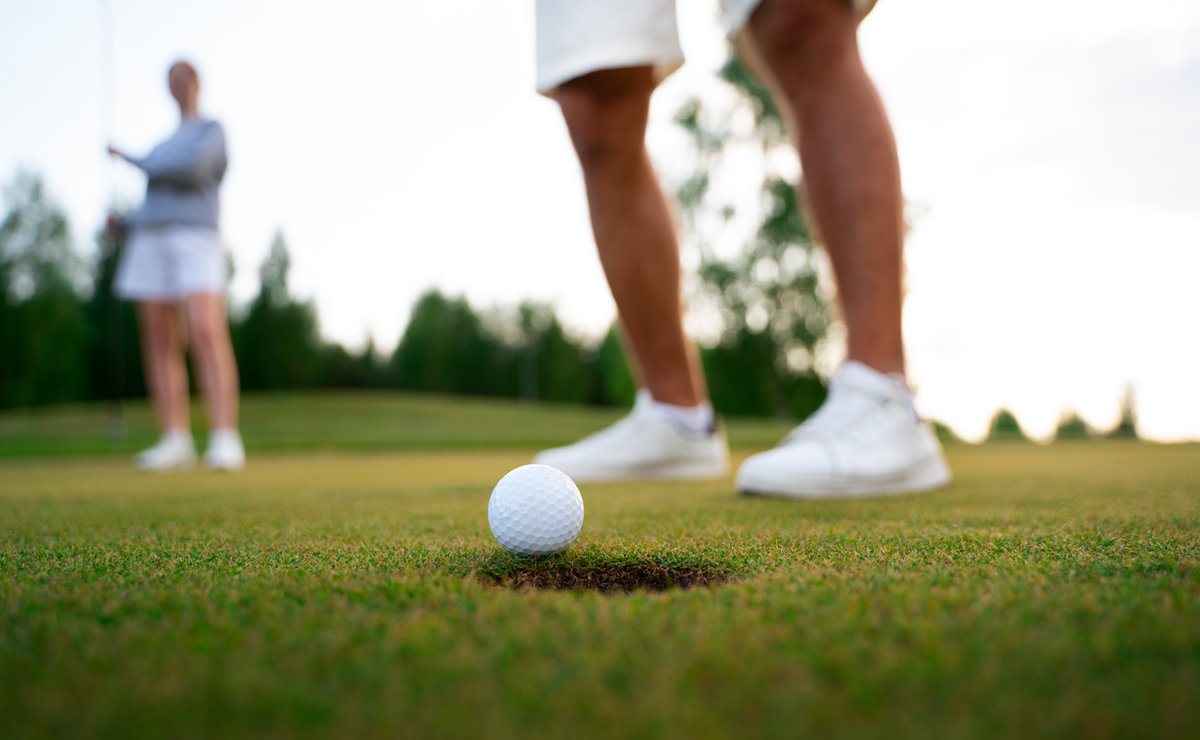 Friends on the putting green, lining up a golf shot